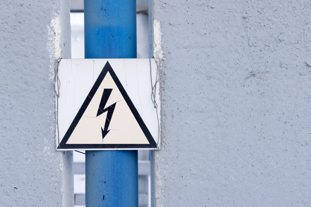 A high voltage sign on the fence of an electrical substation. Warning.
