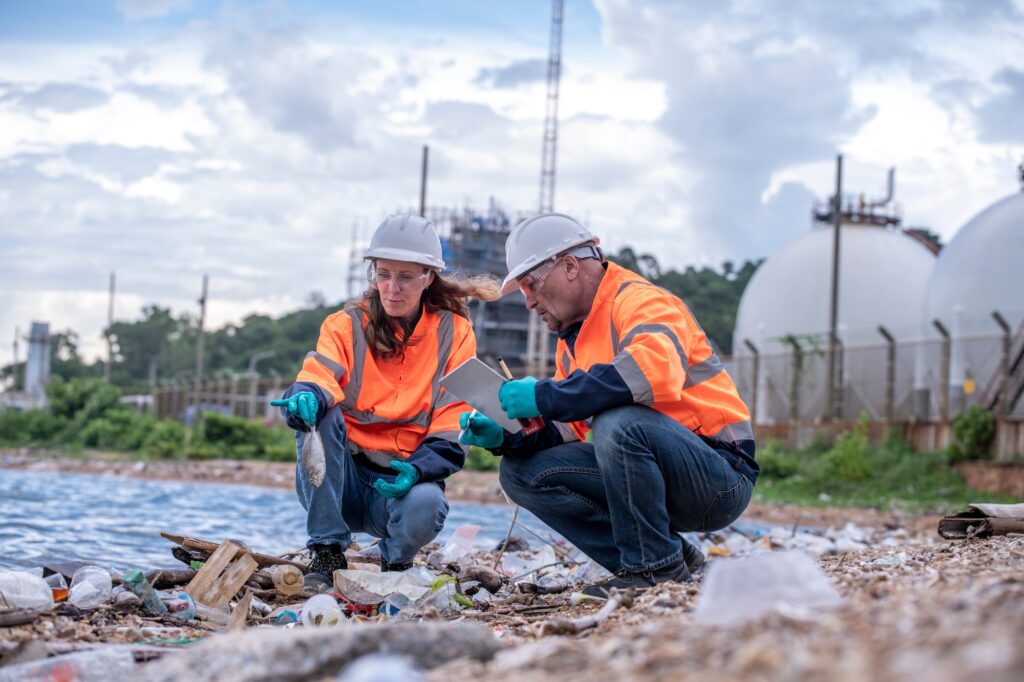 Environmental scientists or workers, wearing safety helmets and gloves, examining waste materials al