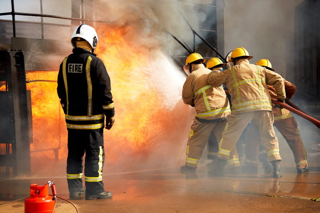 Firemen training, firemen spraying water at fire at training facility, rear view