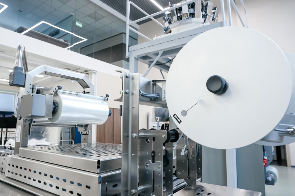 Processing of Packaging equipment thermoformer Packing food in production line. Vacuum machine tool