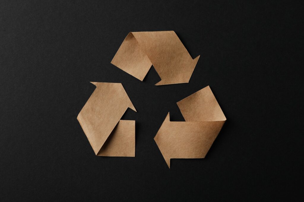 Recycling sign on black background, top view