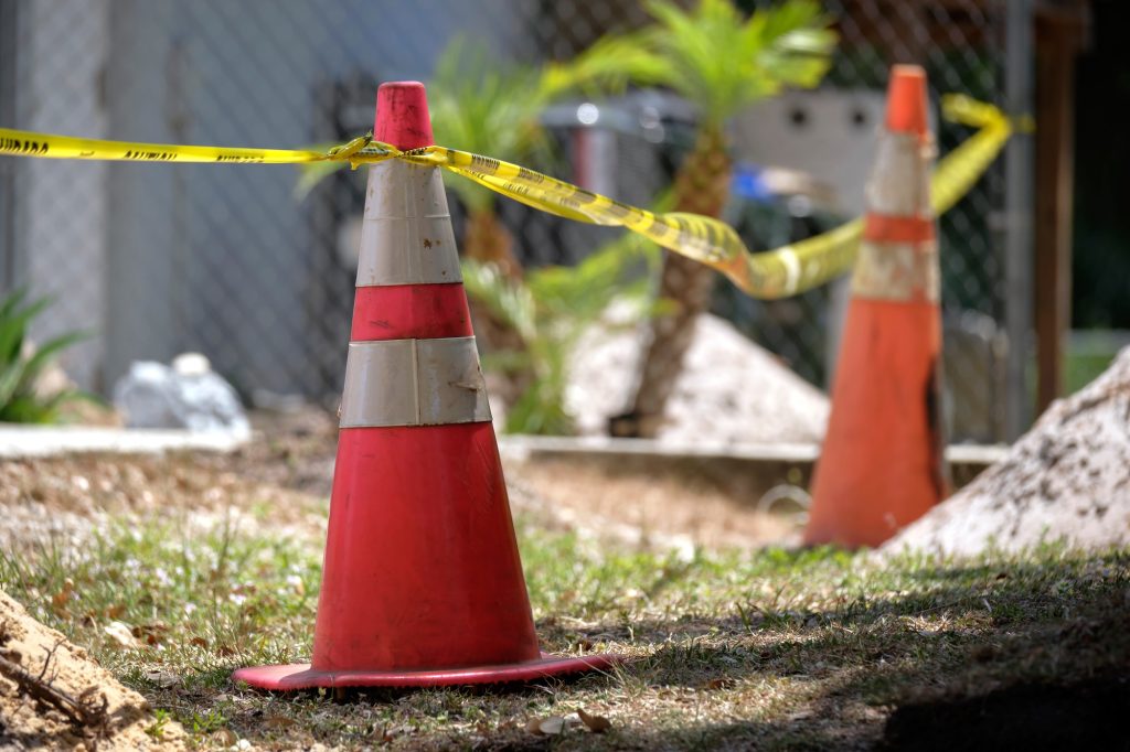 Yellow warning cones and tape as protective restriction barrier at industrial construction